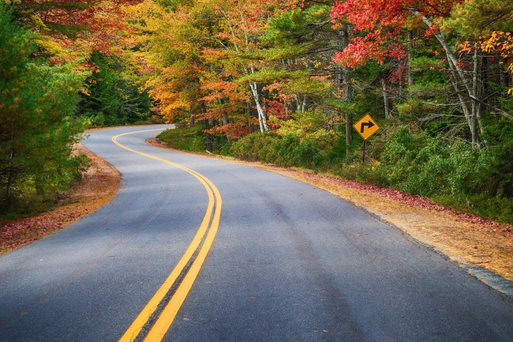 Road Trip through road curves through colorful autumn trees in New England