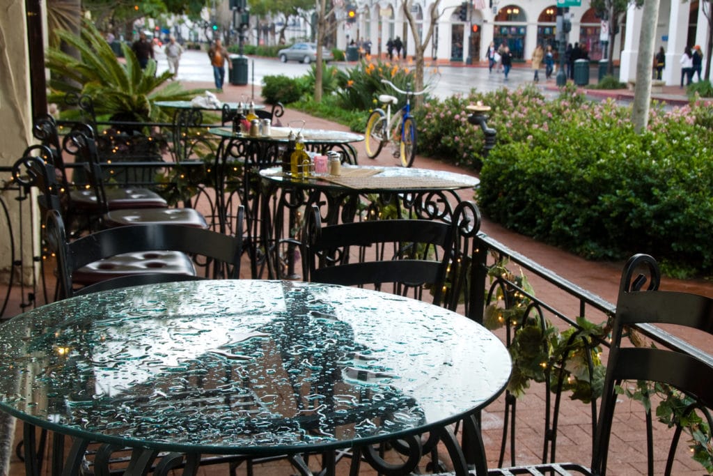 Wrought iron chairs and glass top table setting at sidewalk caf