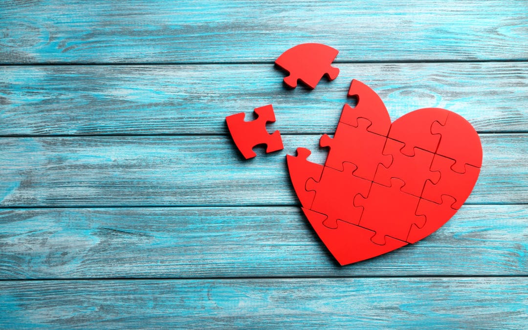 Red puzzle heart on blue wooden background
