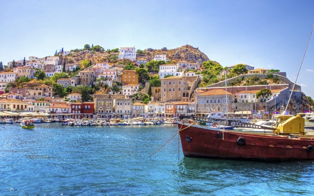 A view of the beautiful Greek island, Hydra. There is a fishing boat on the foreground and some local architecture on the background. The view is from the sea as the cruiship embarked in Hydra.
