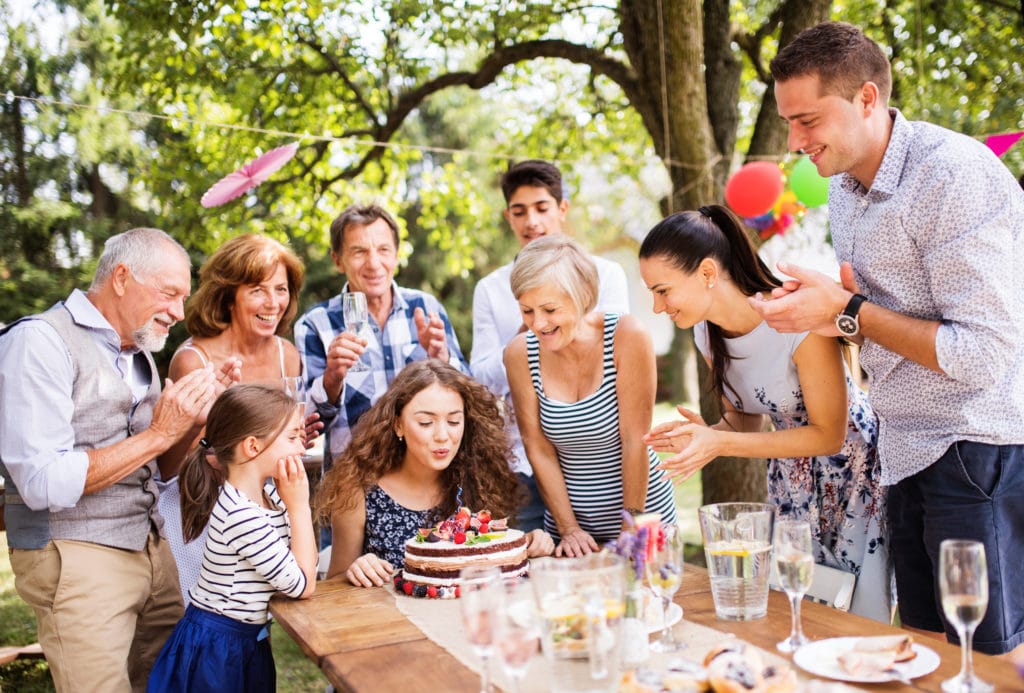 Family celebration outside in the backyard. Big garden party. Birthday party. A teenage girl with a birthday cake.