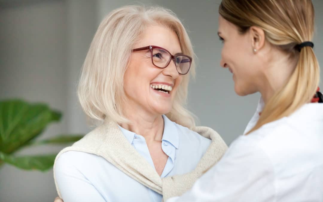Beautiful aged woman in glasses embracing young adult lady and laughing, smiling attractive senior older mother happy to hug grown-up daughter, warm sincere family bonding having fun together